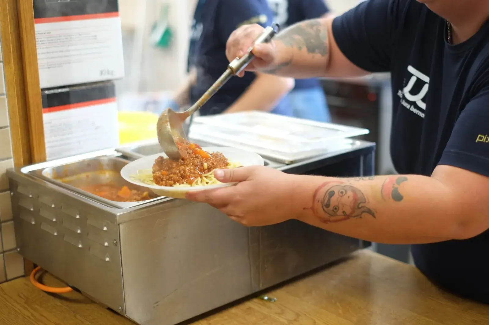 A volunteer serves a plate of pasta in the Marelle kitchen